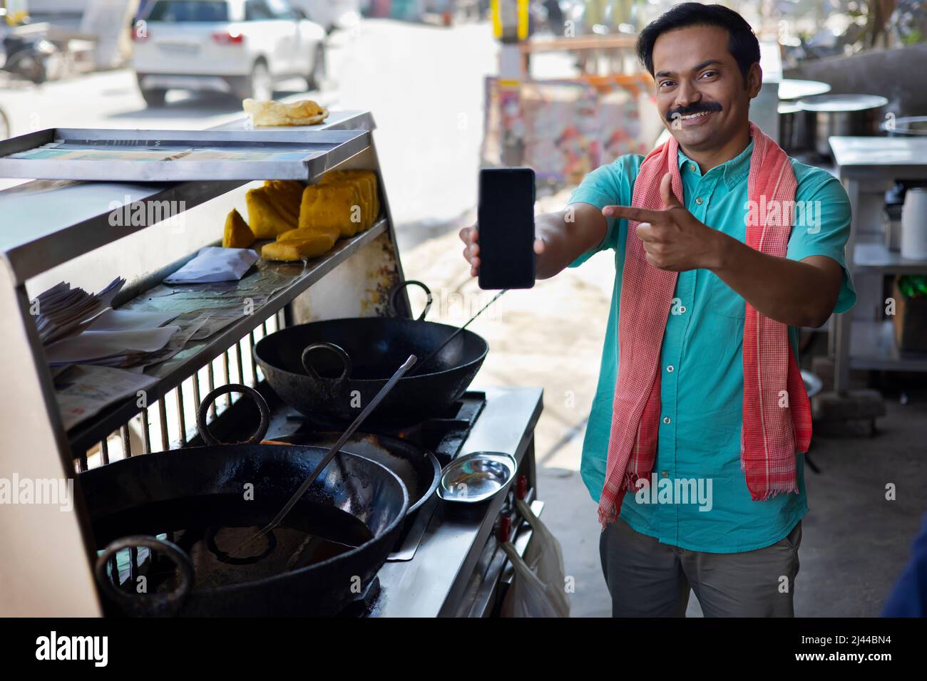 Street food vendor pointing to his Smartphone for contactless payment Stock Photo