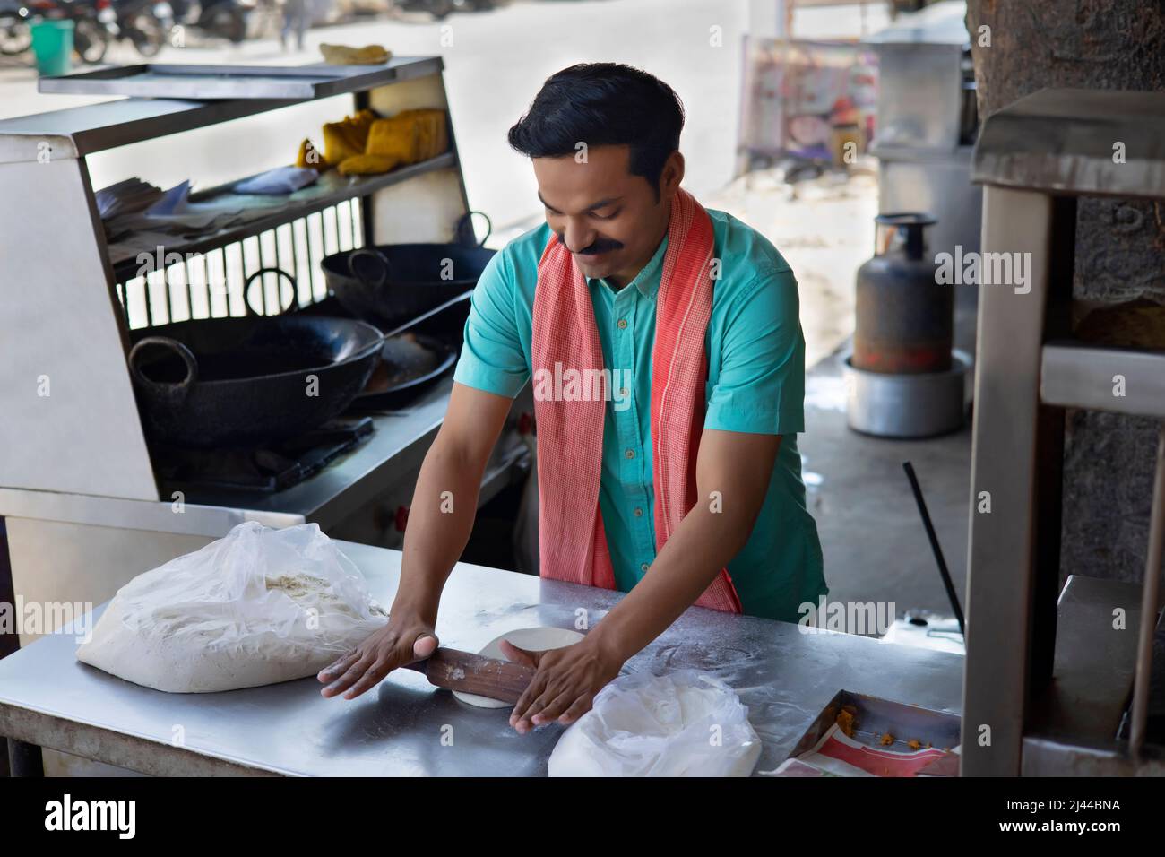 Street food vendor flattening flour dough by rolling pin Stock Photo