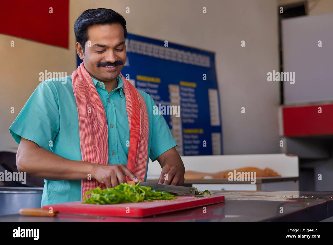 Portrait of a Man chopping capsicum with knife in restaurant Stock Photo