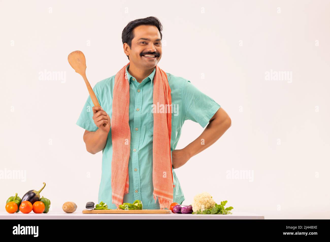 Cook servant posing in front of camera with holding wooden spatula in kitchen Stock Photo