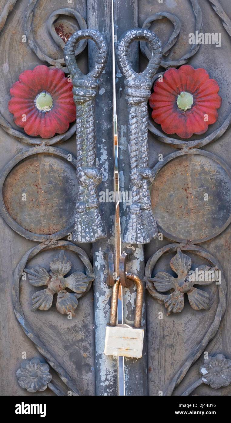 Old vintage brass lock handing from iron forged door handles on carved wooden balinese door in Indonesia Stock Photo
