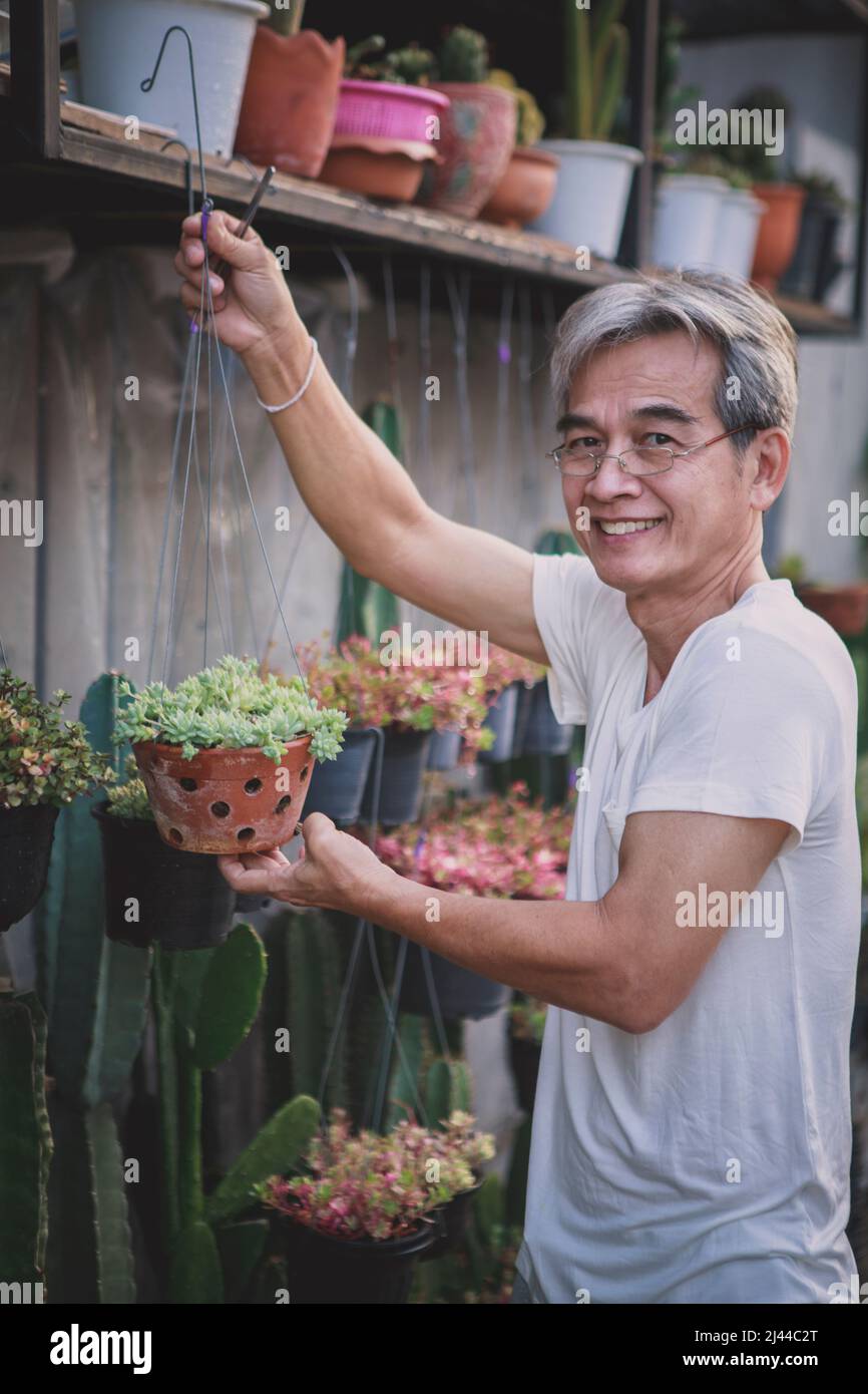 asian holding planting pot toothy smiling with happiness face at home garden Stock Photo