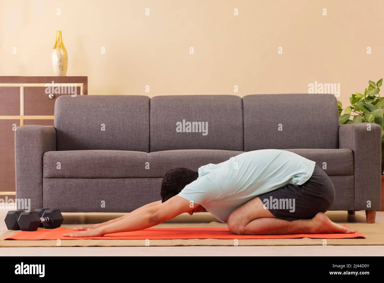 Portrait of a young man doing child pose yoga on exercise mat at home Stock Photo