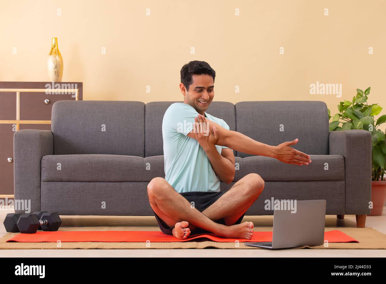 Male Indian Yoga instructor conducting an online class with laptop Stock Photo