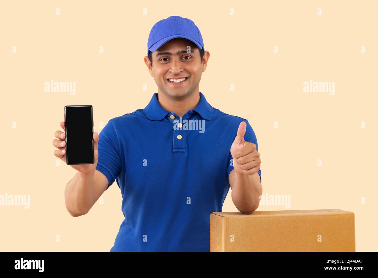 Portrait of a courier delivery boy showing Smartphone and gesturing with thumb Stock Photo