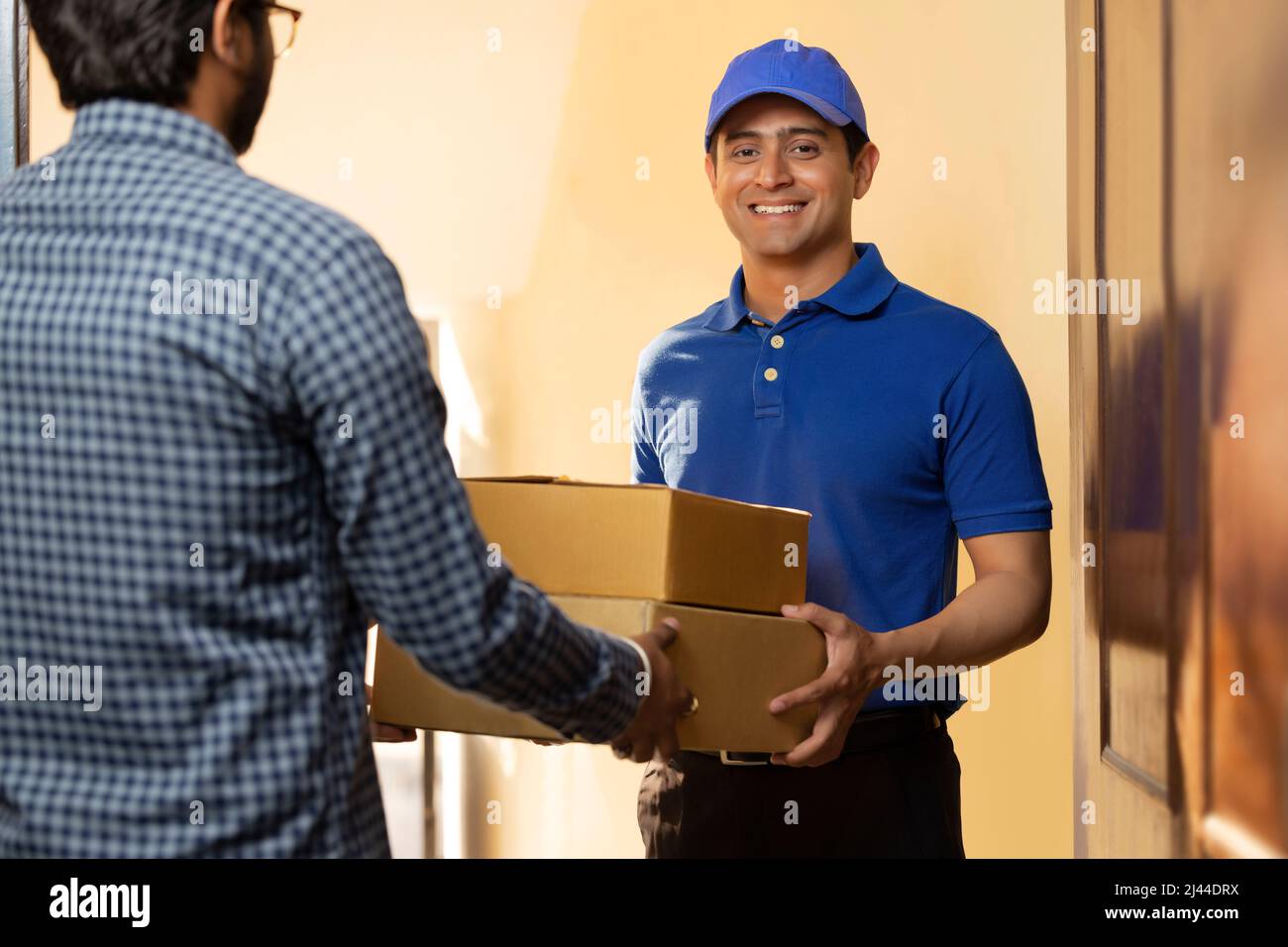 Young courier boy delivery parcels to customer at door Stock Photo Alamy