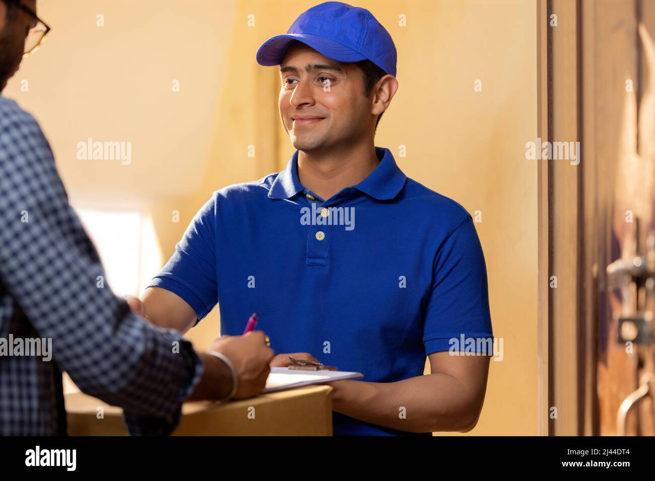 Customer signing the receipt after receiving his parcel from the delivery boy Stock Photo