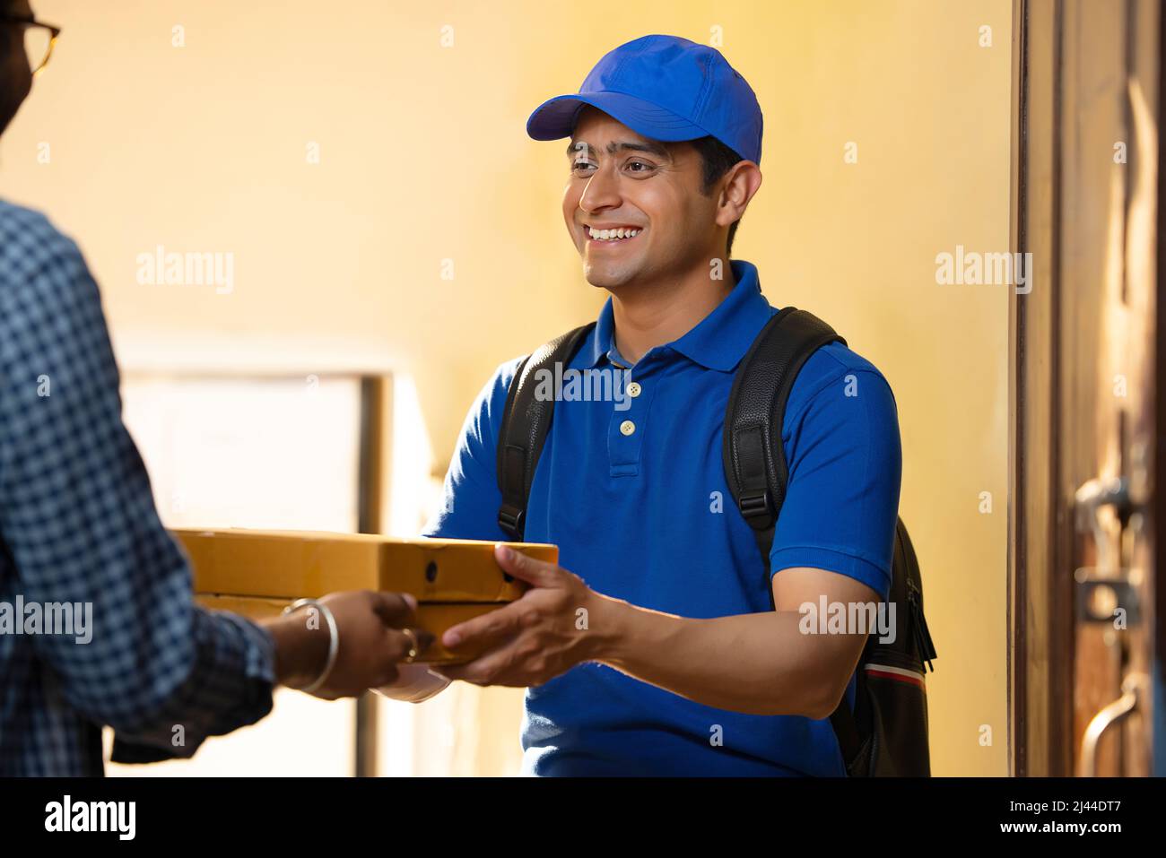 Young courier boy delivery parcels to customer at door Stock Photo