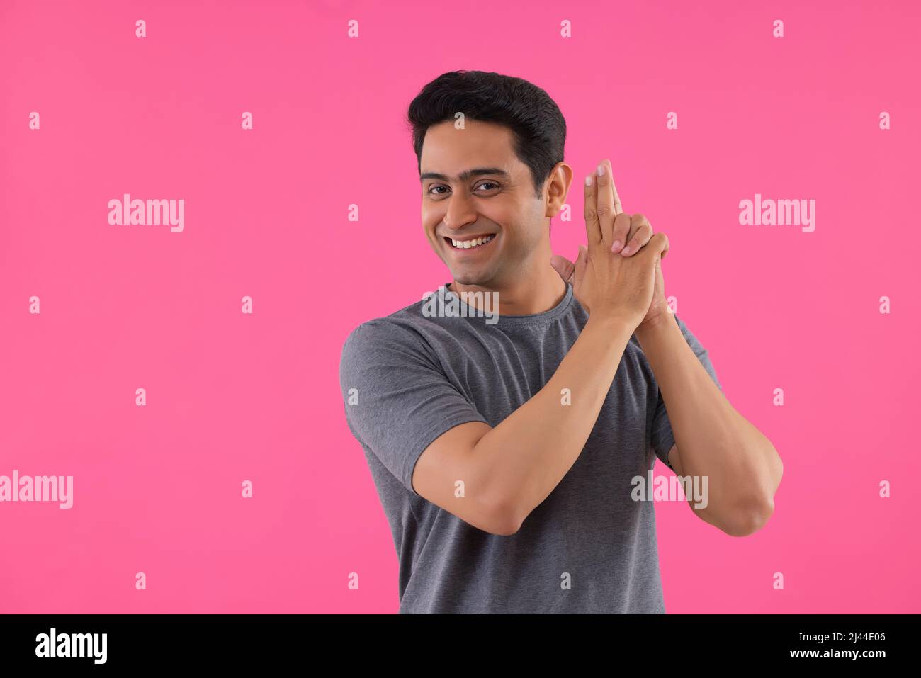 Portrait of a happy young man making shooting gesture by his hands Stock Photo