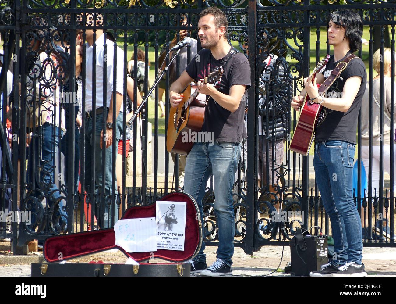 Young street performers playing acoustic music with guitars in the