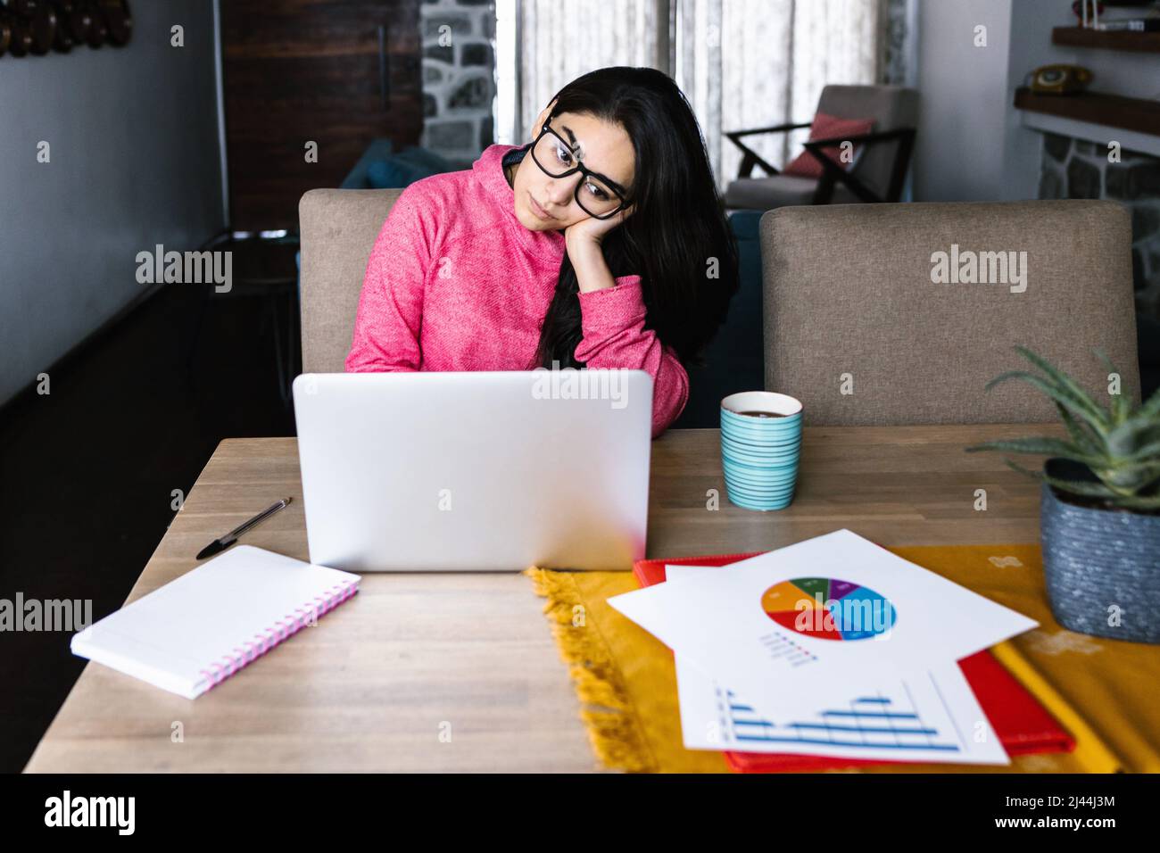 Latin woman in front of her laptop staring at the screen, bored, sleepy, tired in a home office concept in Mexico Latin America Stock Photo