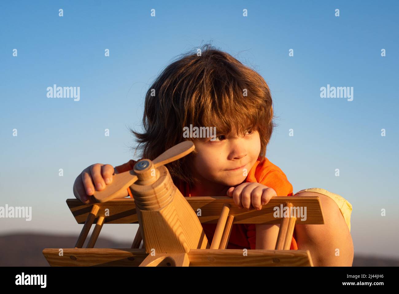 Child boy playing with wooden toy airplane, dream of a pilot