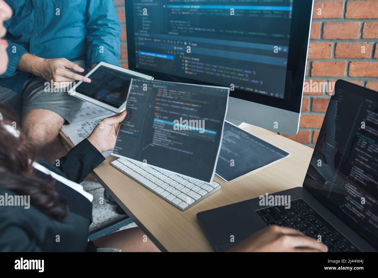 Two software developers are analyzing together about the code written into the program on the computer. Stock Photo