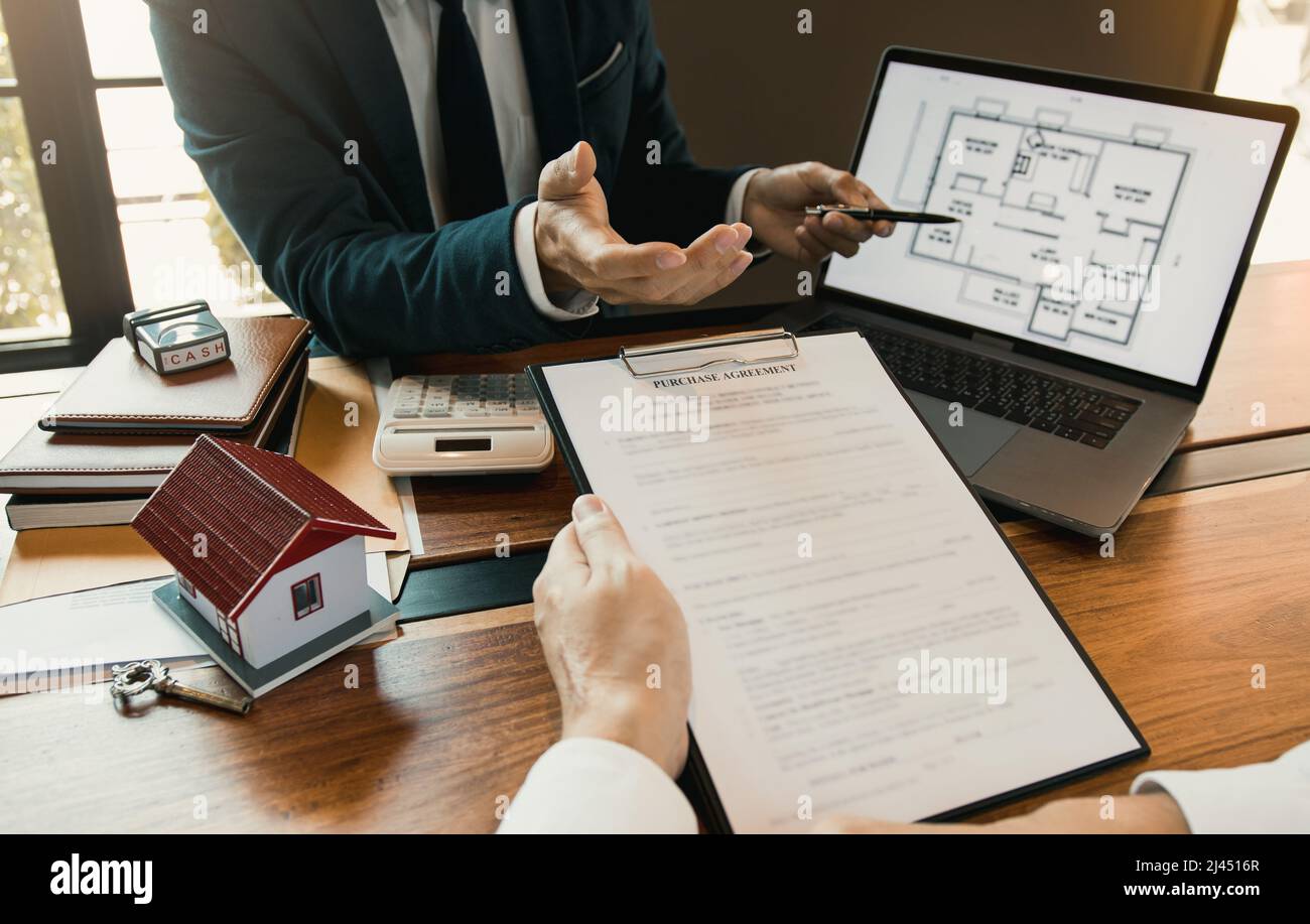 Agents are using pens pointing to blueprint home design on laptop ...