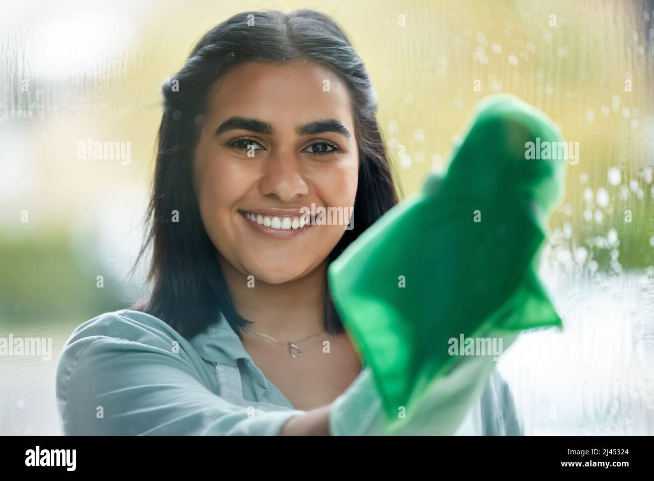 Wipe from left to right. Shot of a young woman cleaning her windows