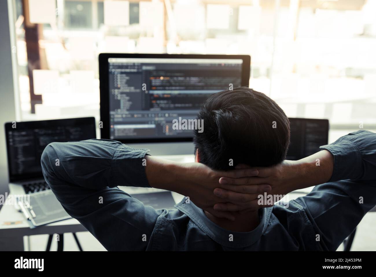 Asian programmers man are relaxing and looking at the code on the computer screen in the office. Stock Photo