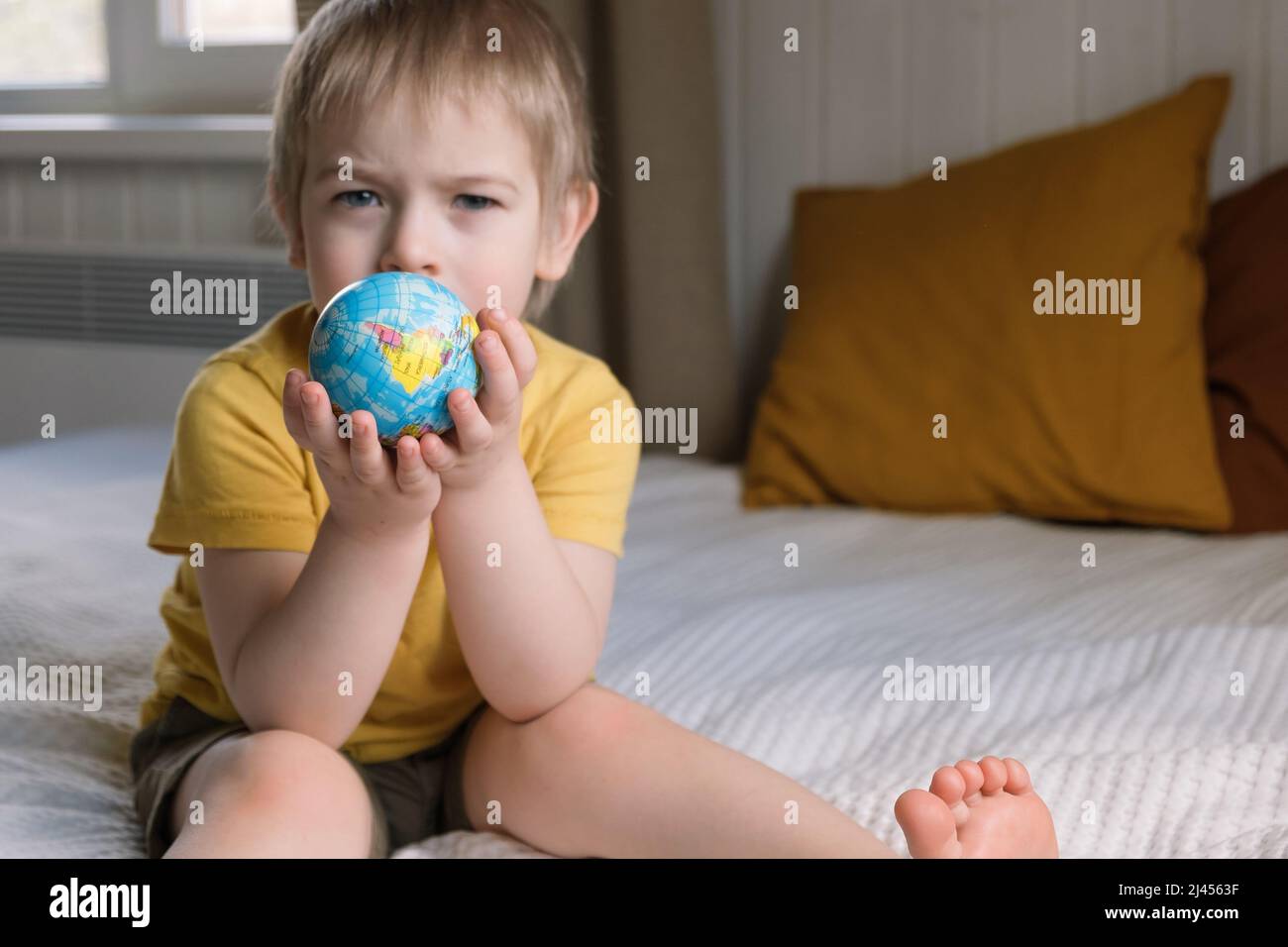Child boy with blonde hair hugging earth globe, save earth concept. 3 years old kid holding globe model. Baby toddler. Children education development Stock Photo