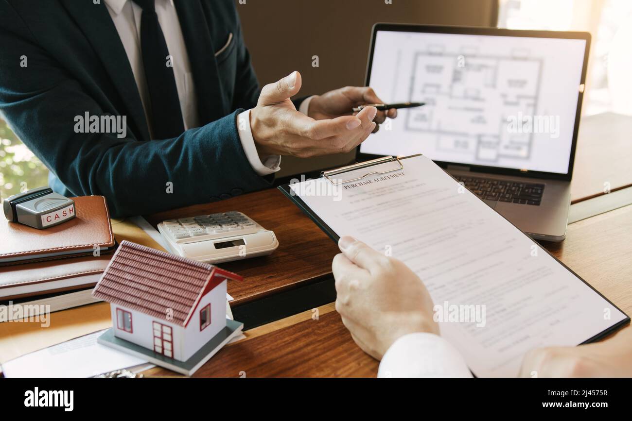 Agents are using pens pointing to blueprint home design on laptop ...