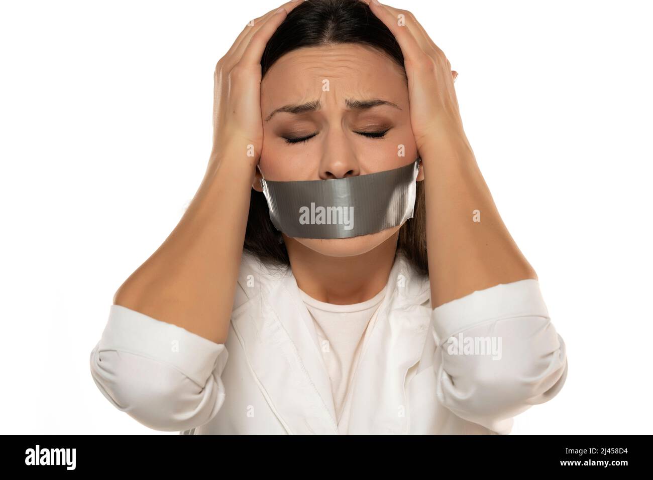 Unhappy young woman with adhesive tape over her mouth on a white