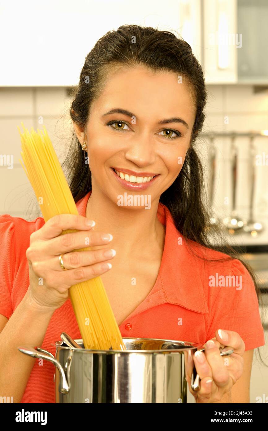 Bruenette Frau kocht mit Spass am Essen Spaghetti in der Kueche Stock Photo