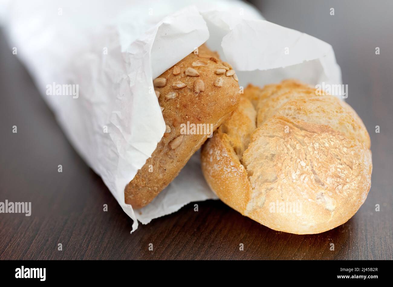 fresh crispy bread rolls in paper bag on brown table Stock Photo