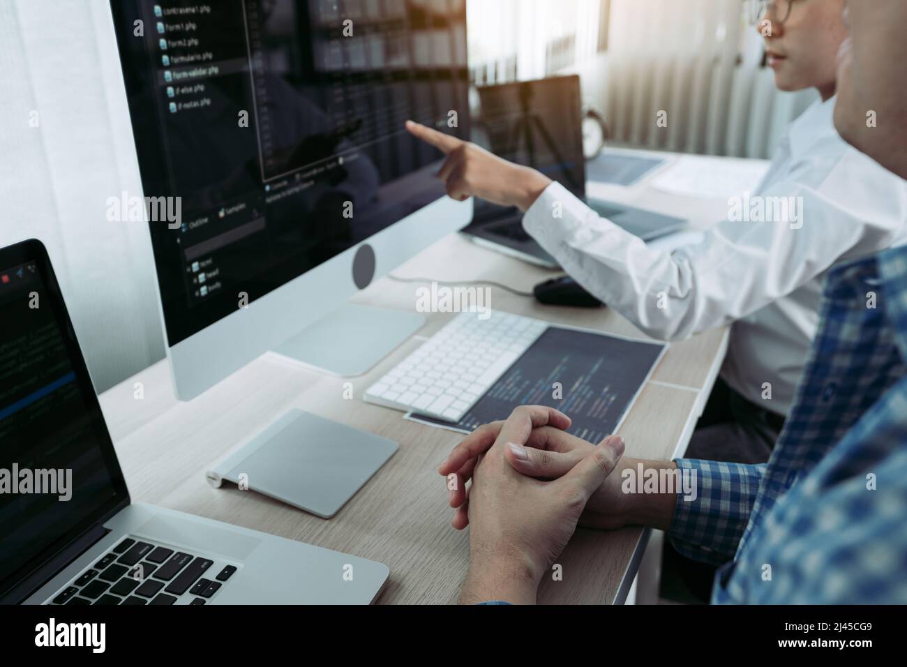 Two partnerships developing programming and coding technologies working on laptop and analyzing together. Stock Photo
