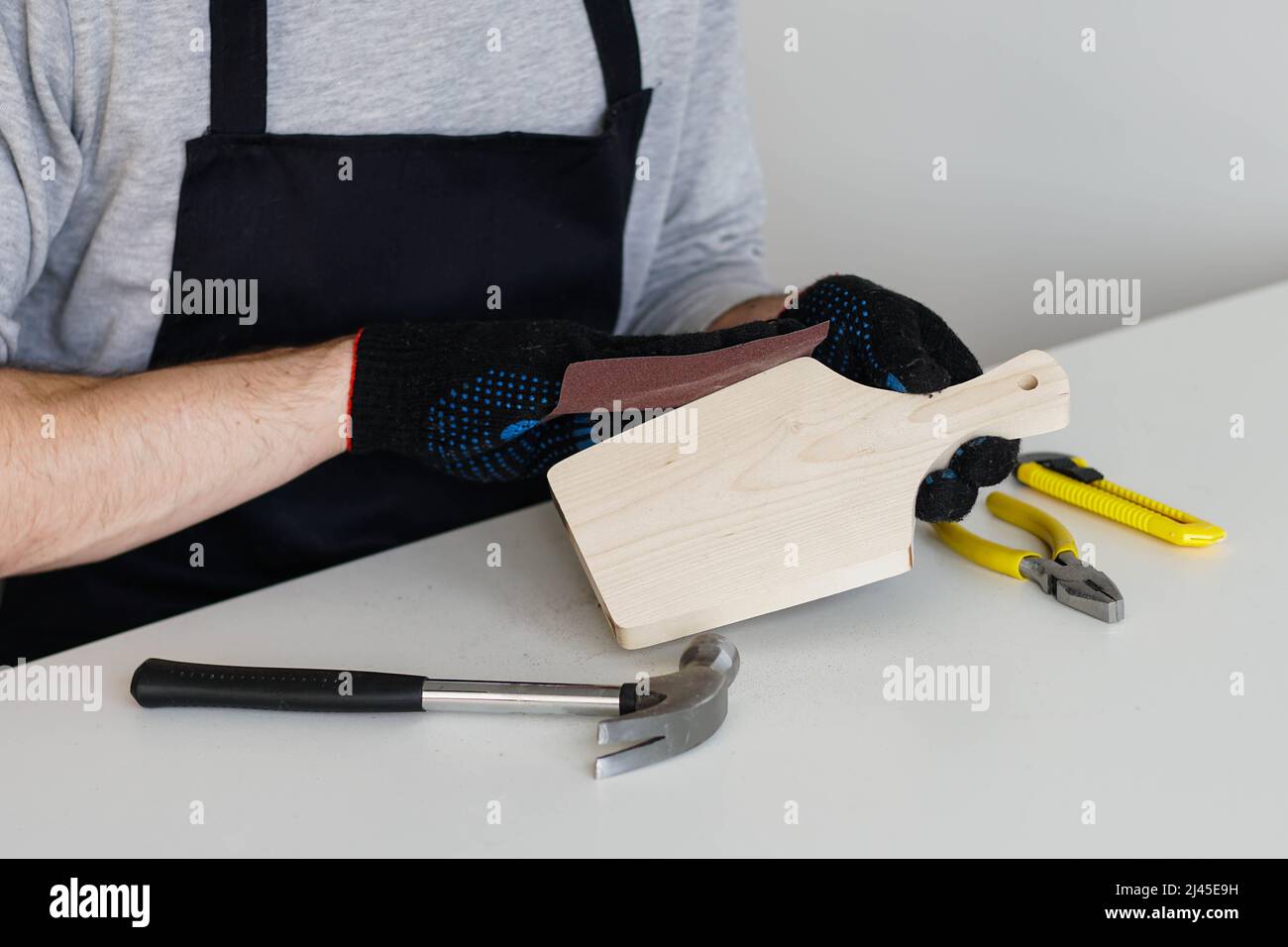 Carpenter hands polishing wooden cutting board with sandpaper close up
