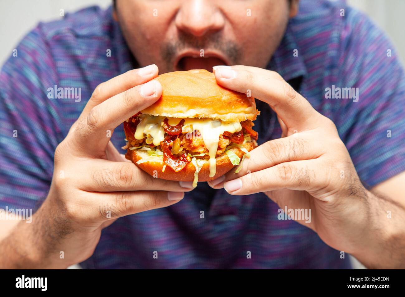 Eastern man looking at crispy chicken burger and is about to eat it. Stock Photo