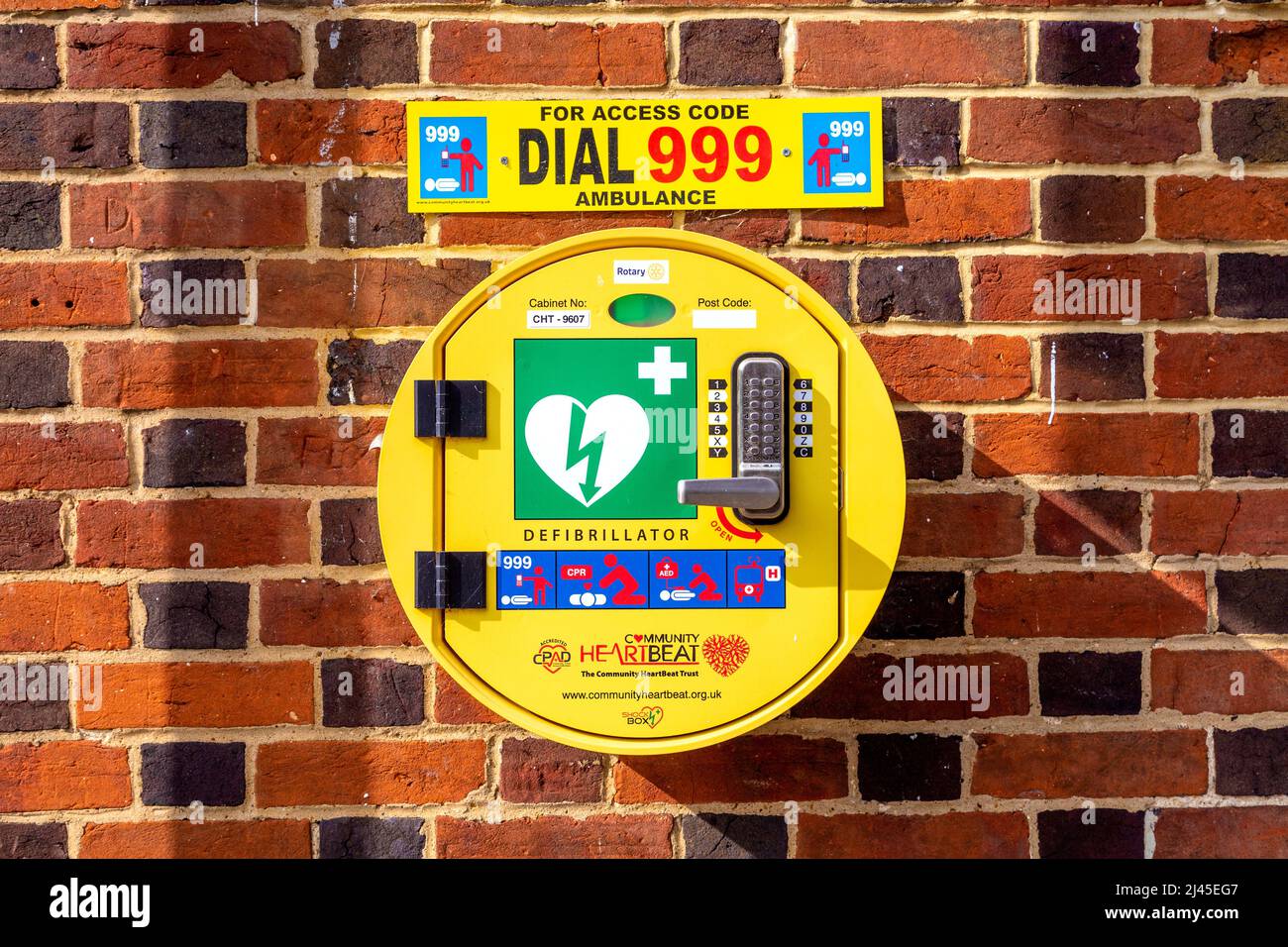Code locked emergency defibrillator mounted on a brick wall Stock Photo