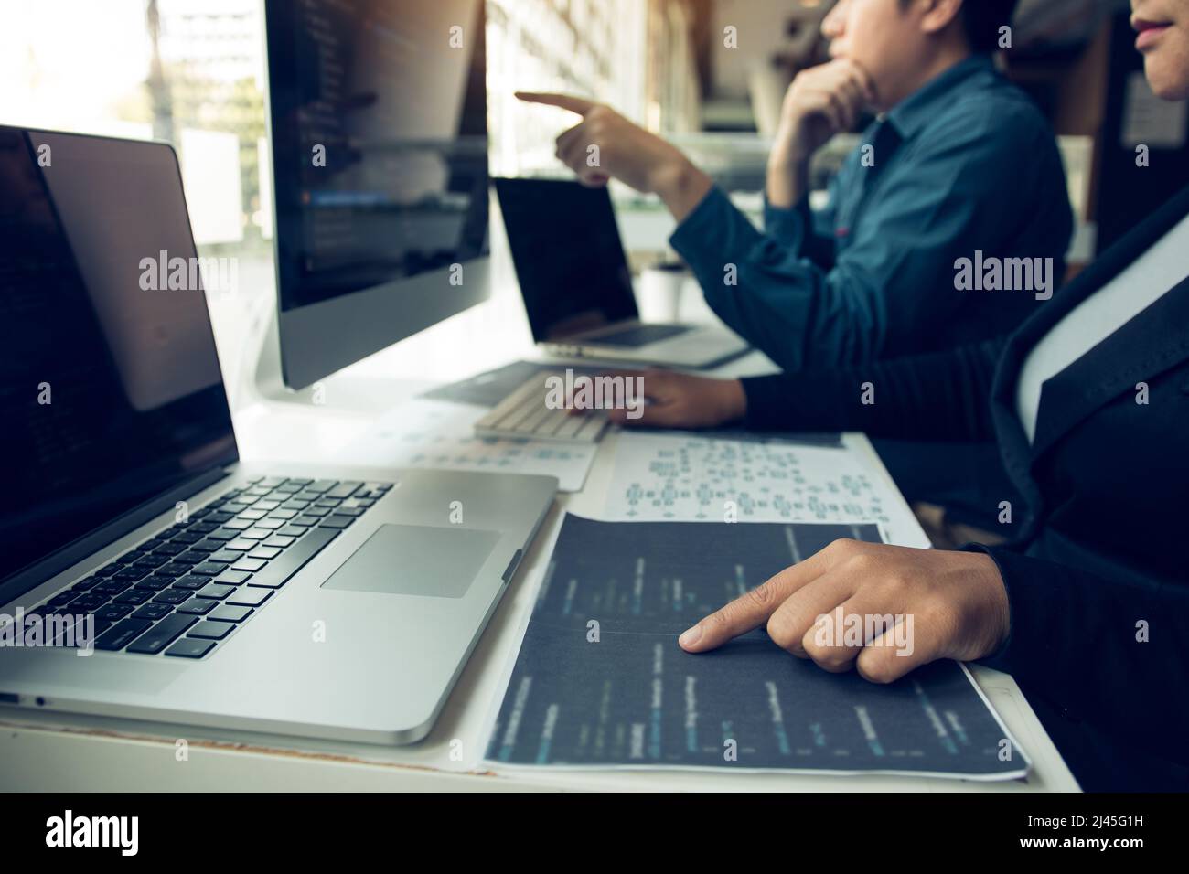 Two software developers are analyzing together about the code written into the program on the computer. Stock Photo