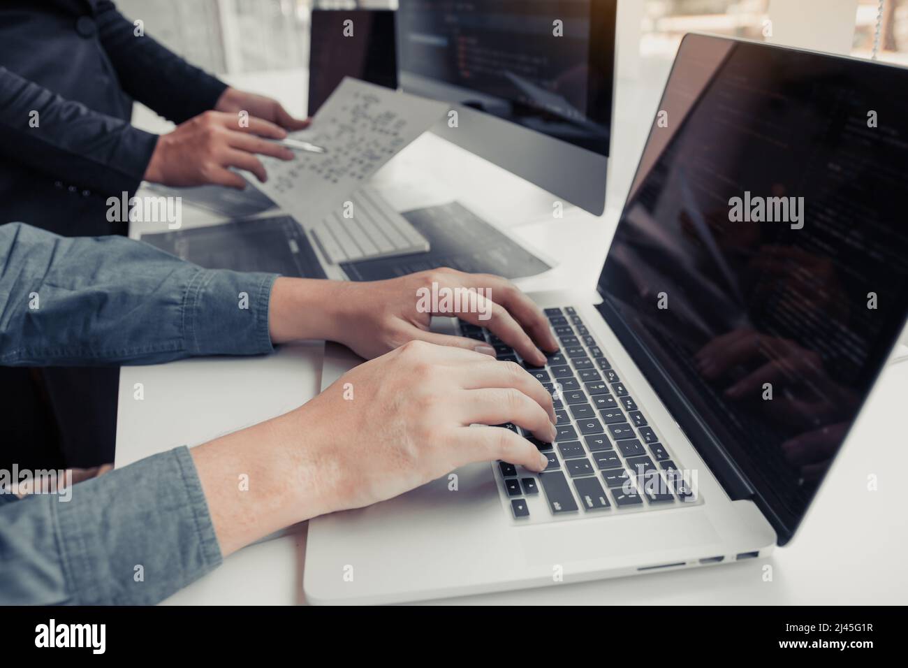 Two partnerships developing programming and coding technologies working on laptop and analyzing together. Stock Photo