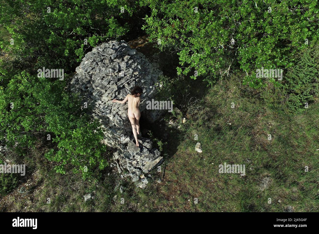 Drone aerial view of a naked woman in the middle of the nature, near a dry-stone hut Stock Photo