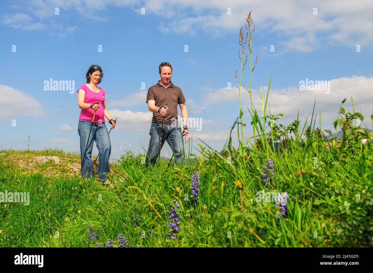 Active couple with pregnant woman on the way with Nordic Walking poles Stock Photo