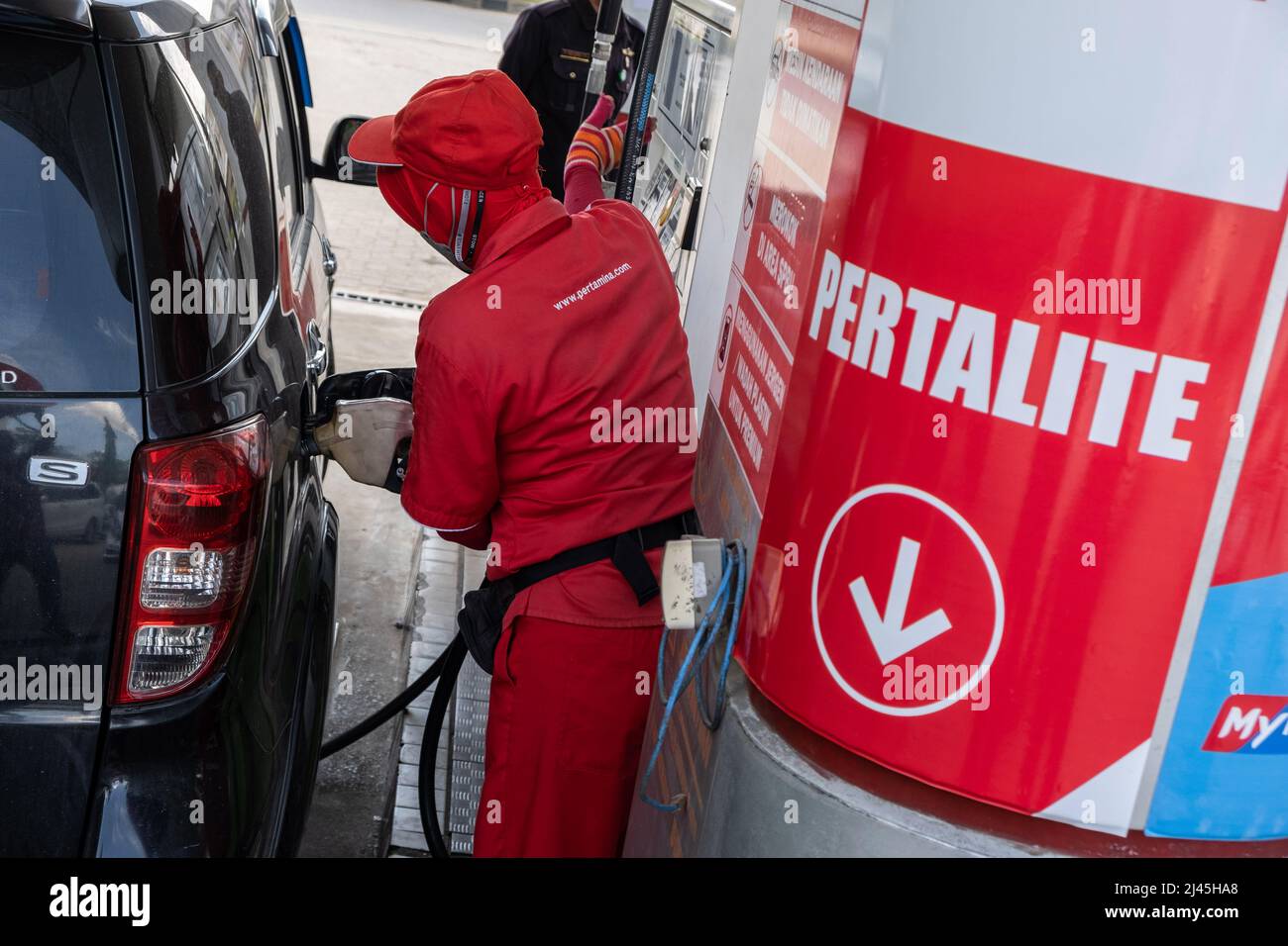 A worker refills a customer's car with pertalite type of fuel