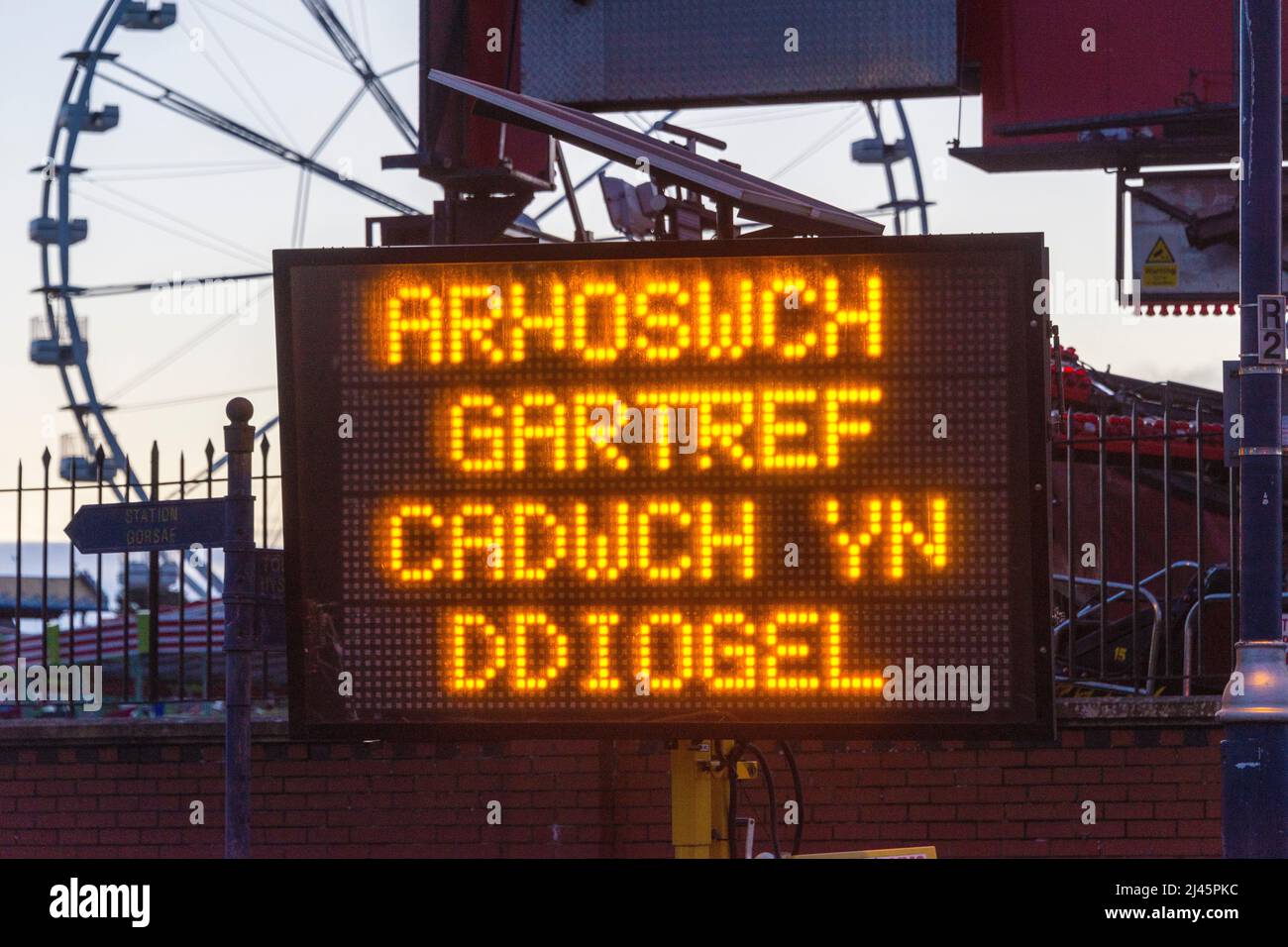 Transportable illuminated sign at Barry Island during Covid 19 pandemic. Message in  Welsh arhoswch gartref cadwch yn ddiogel, stay home stay safe. Stock Photo