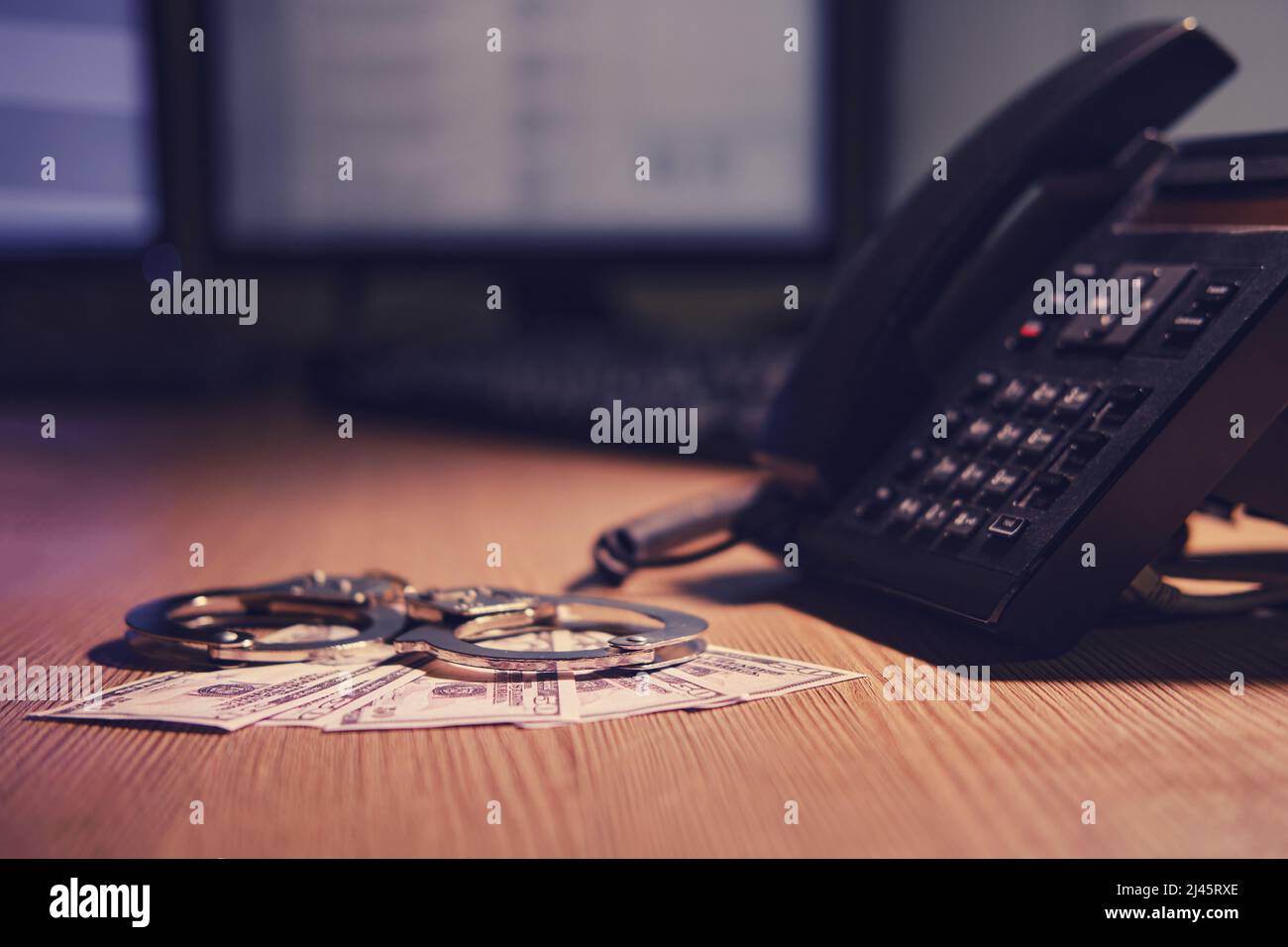 Landline phone and cash dollars with handcuffs on the table, closeup