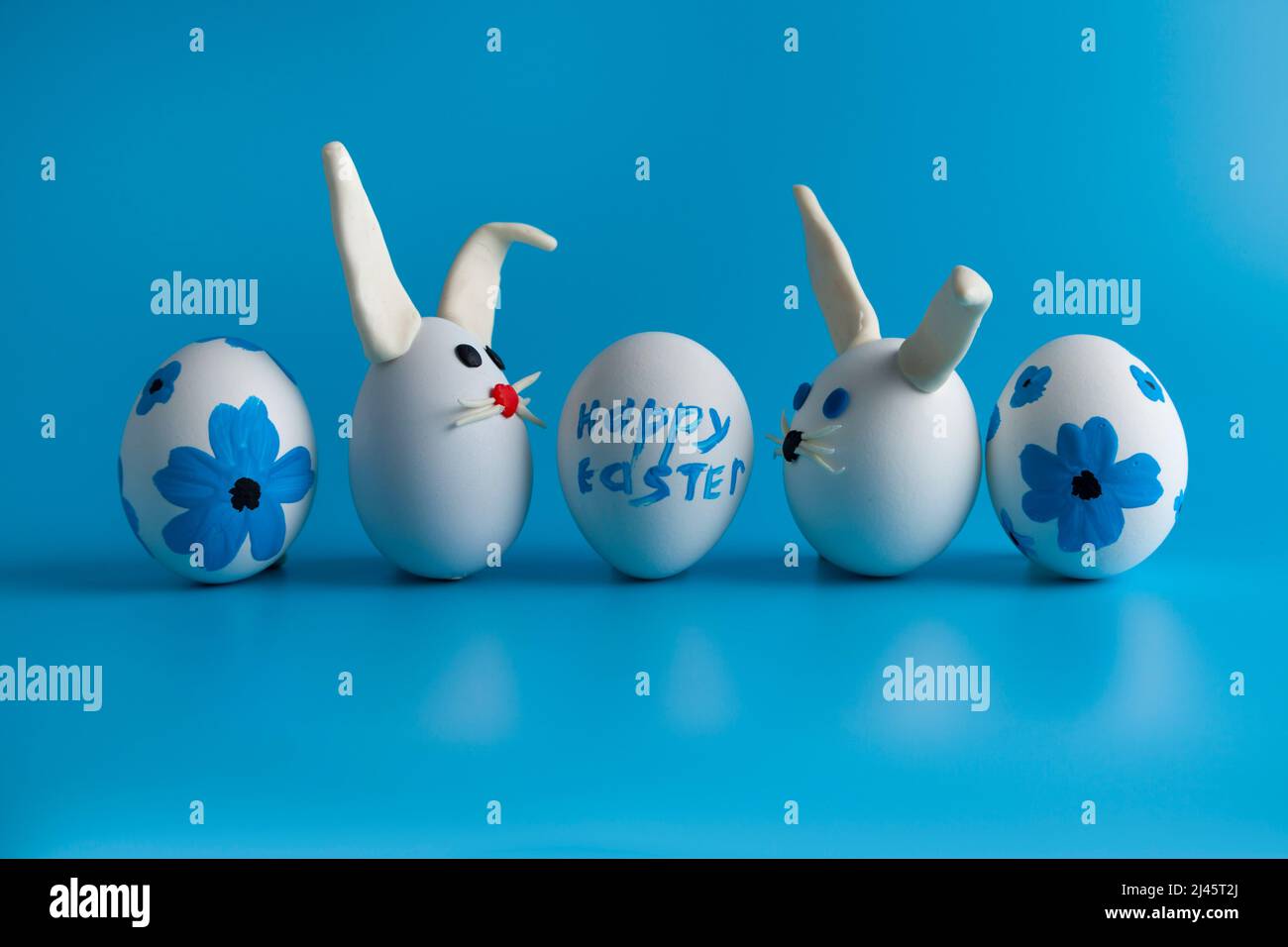 Easter composition with Easter eggs decorated flowers and Easter bunny. Blue background, copy space. Stock Photo