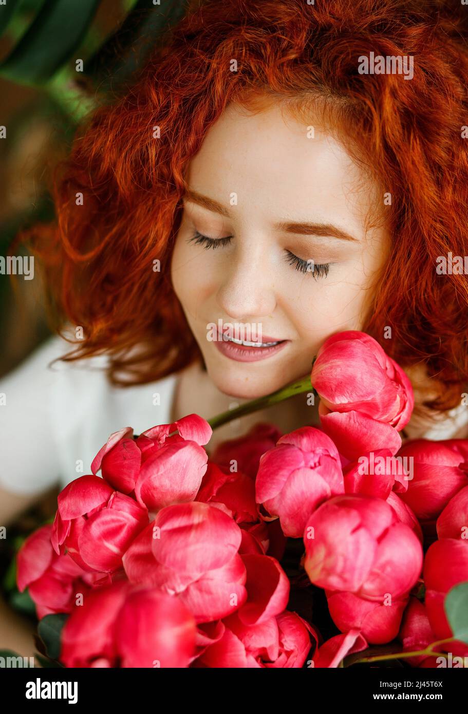 Dreamy curly girl holding a bouquet of pink peonies Stock Photo - Alamy