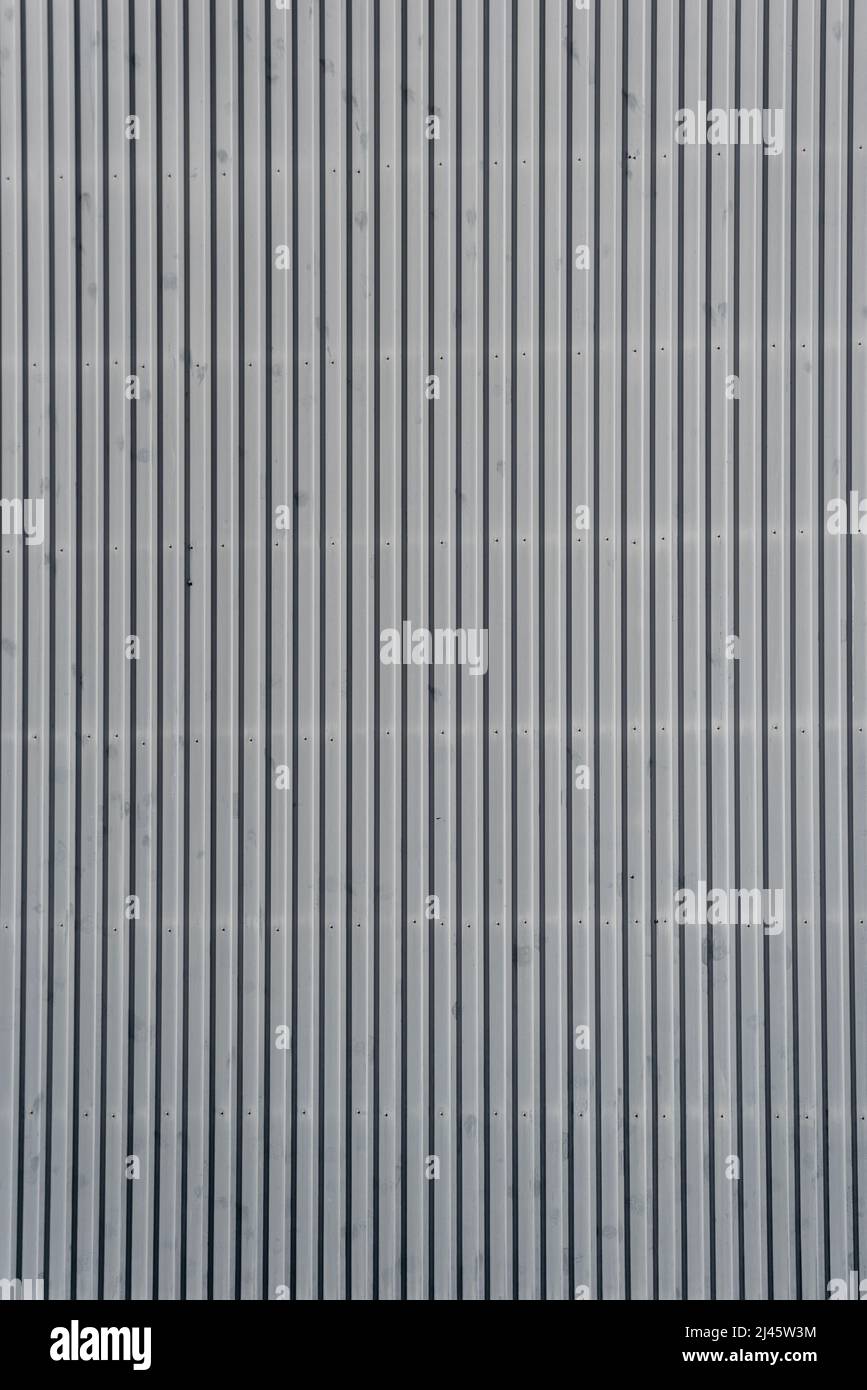 Architectural detail in close-up of grey corrugated steel industrial building facade with vertical lines forming symmetric abstract pattern Stock Photo