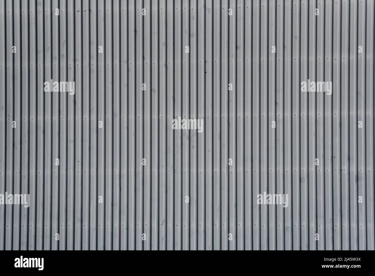 Architectural detail in close-up of grey corrugated steel industrial building facade with vertical lines forming symmetric abstract pattern Stock Photo
