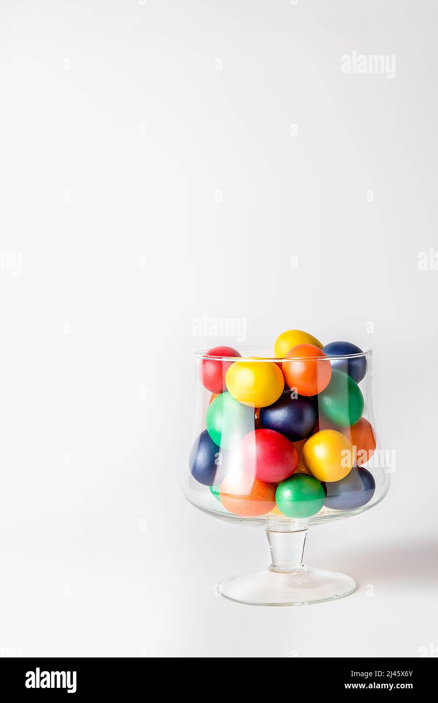 Multicolored painted eggs in a glass vase. Easter concept. A ready place for your invitation text, congratulations. Stock Photo