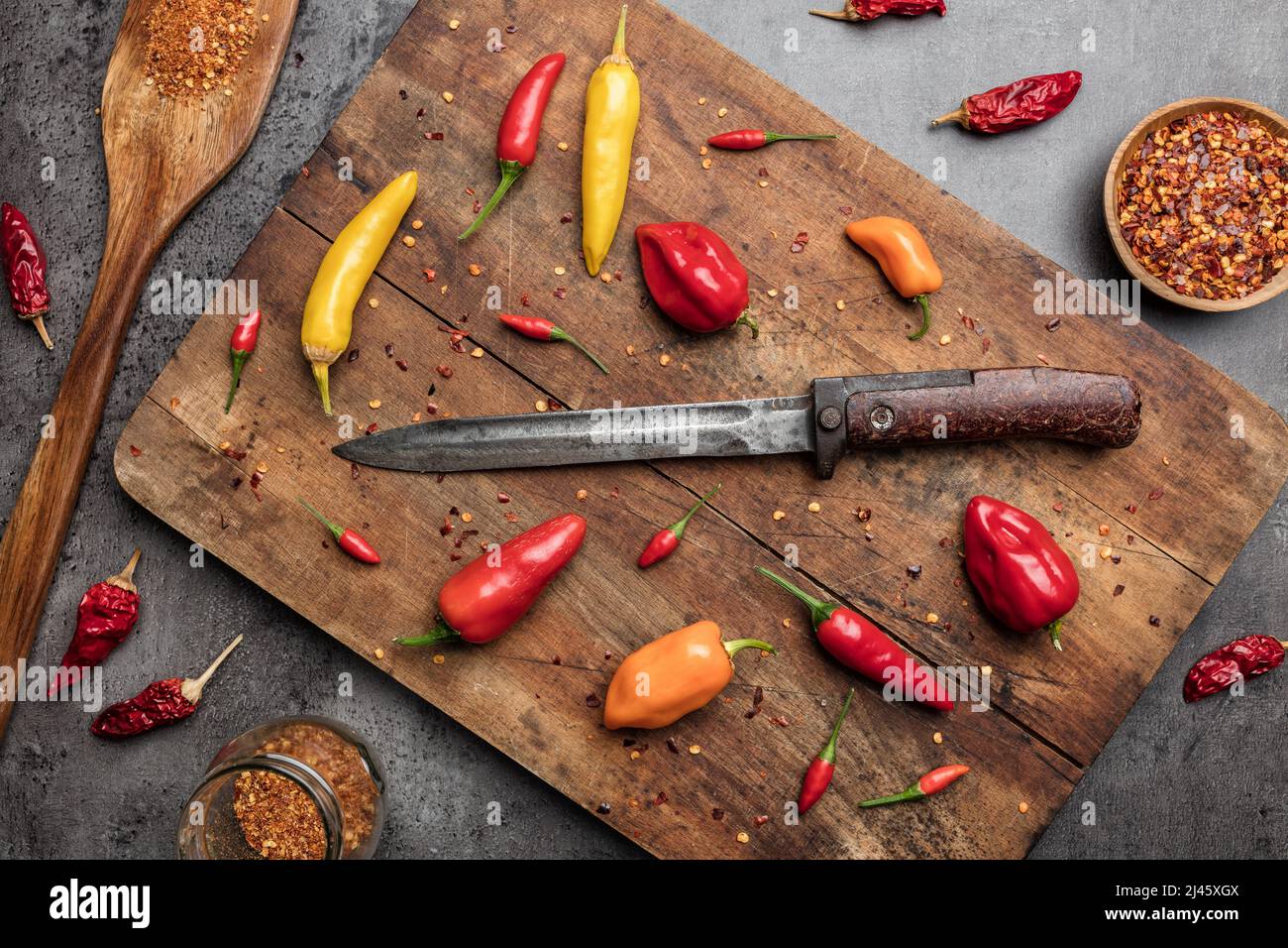 Variety of fresh and dried chili peppers on rustic background Stock Photo