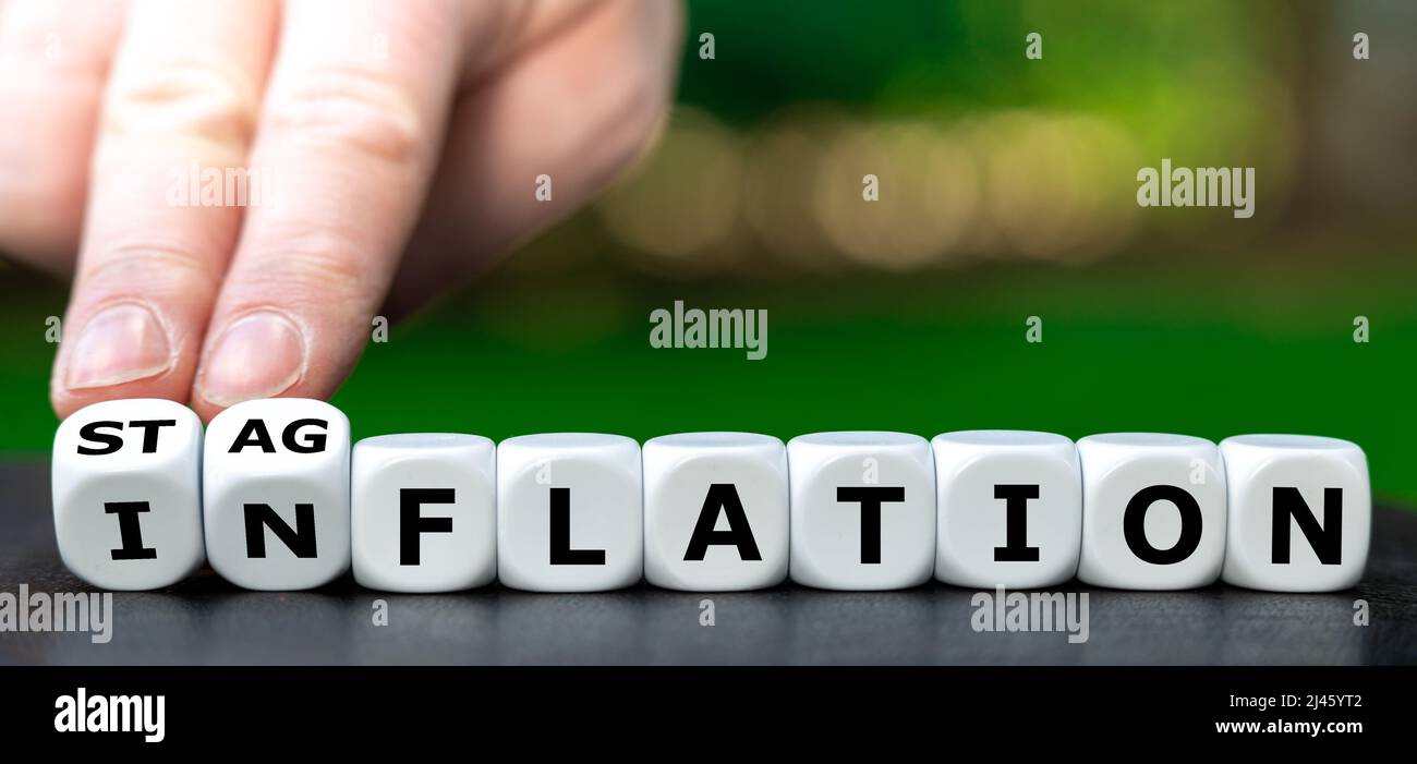 Hand turns dice and changes the word 'inflation' to 'stagflation'. Stock Photo