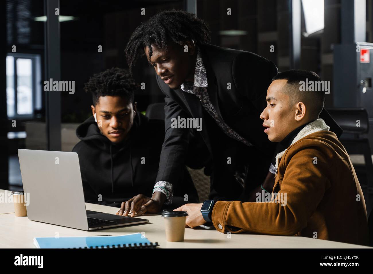 Mixed race of men teamwork on laptop in office. Discussing and working