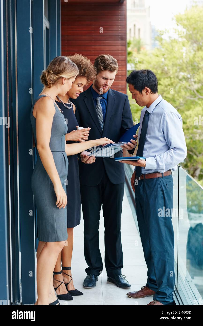 Step outside the box and have a meeting outside. Shot of a group of professionals using a digital tablet together outside of the office. Stock Photo