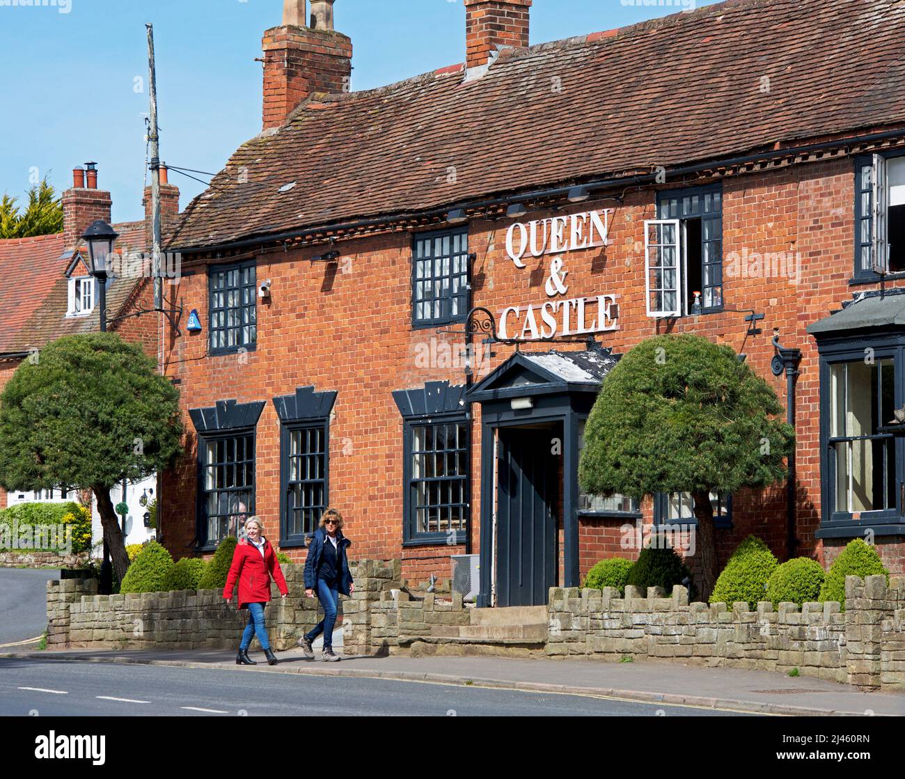 Two women walking past the Queen & Castle pub on Castle Green in Kenilworth, Warwickshire, England UK Stock Photo