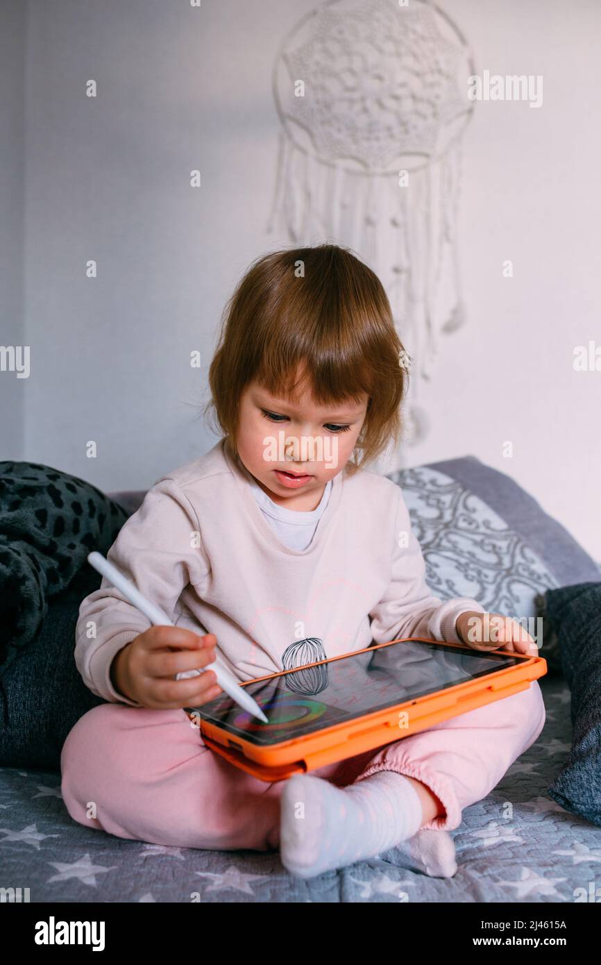 Child using technology. Toddler at home with a tablet and a pen stylus ...