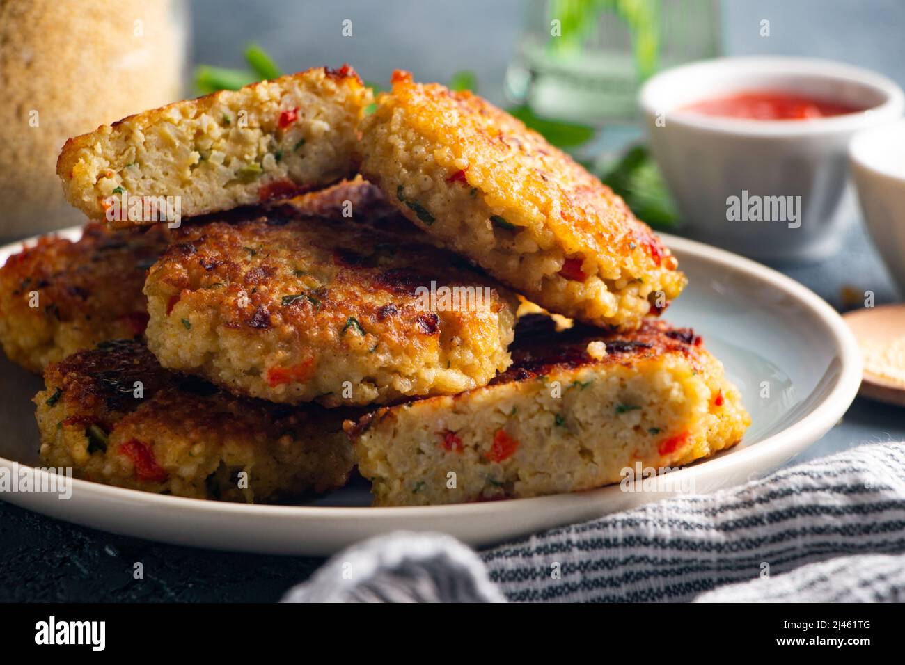 Gluten free vegetarian millet and vegetable burgers served with tomato
