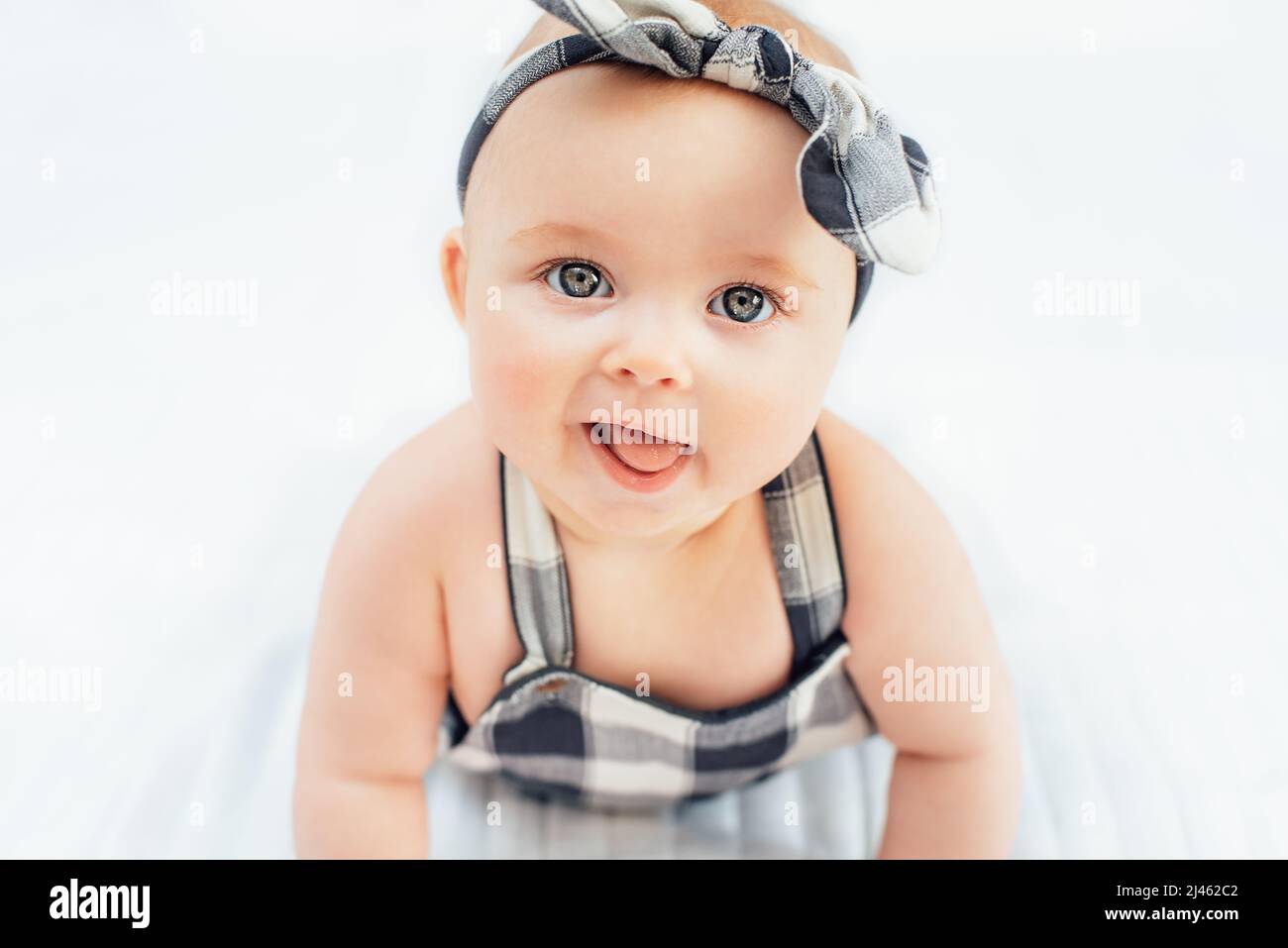 Seven month old baby child sitting on bed. Cute smiling little infant