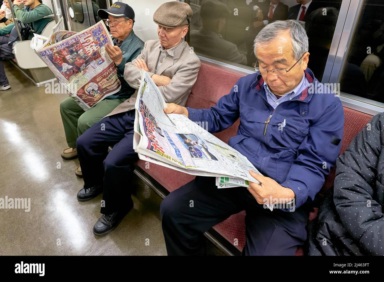 Japan. Tokyo. Passengers on the subway, reading the newspaper Stock Photo